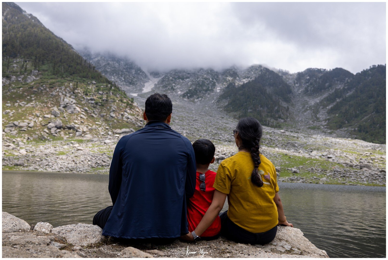 Yuvan between Ma and Papa, sitting together at the edge of the lake