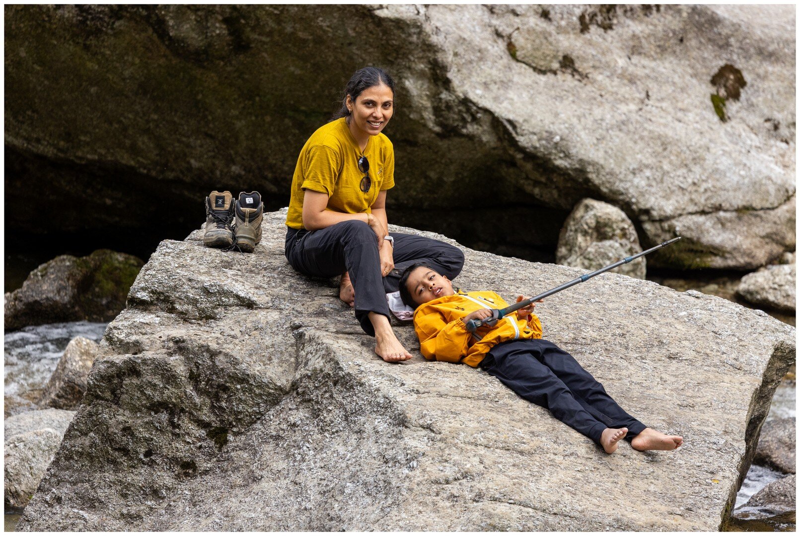 Yuvan lying on the big rock next to Ma by the stream